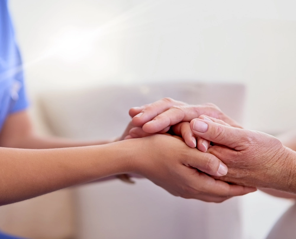 Eine Betreuerin hält die Hände einer Seniorin